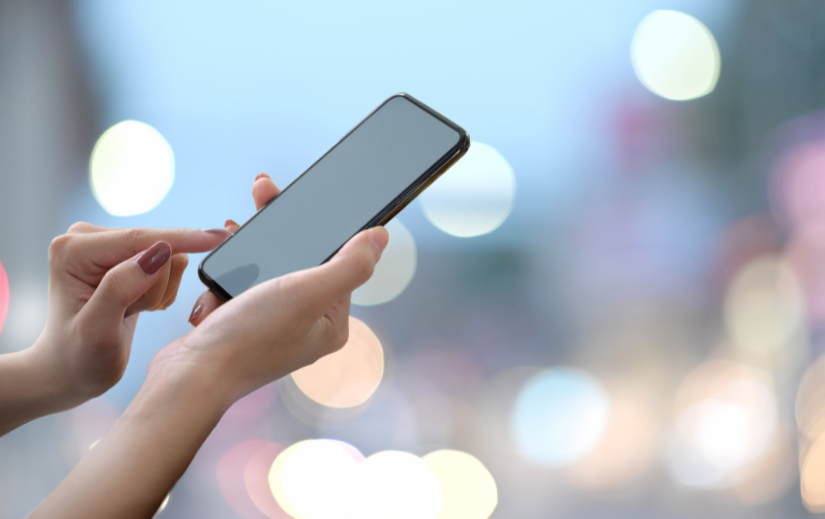 Woman easily making a mobile purchase due to eCommerce site optimization, with a city lights backdrop.